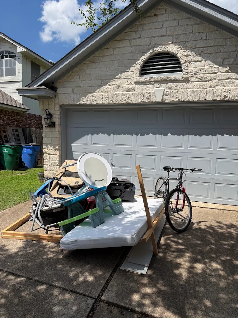 Mattress and junk set out in a driveway for pickup